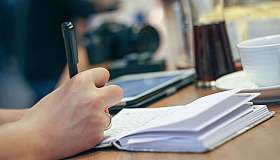 Hand schreibt im Notizbuch