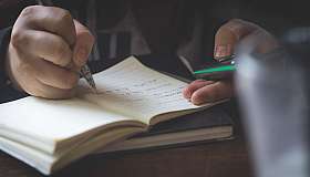 Hand schreibt im Notizbuch
